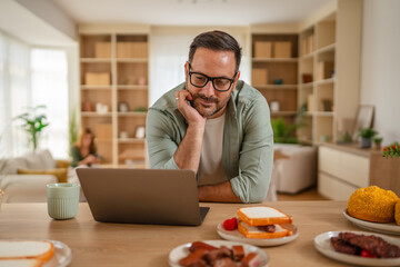 Man working from home having breakfast with laptop