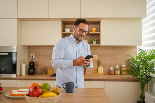 Man checking smart phone in modern kitchen during breakfast