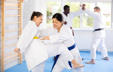 Sportive middle-aged woman trainee of karate courses applying attack methods on her partner