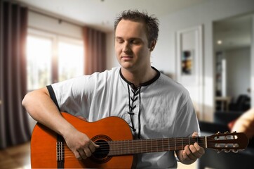 Obraz premium Young happy man play guitar at home.