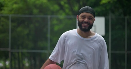 African American man smiling and holding basketball on outdoor court, moment of joy and relaxation after game symbolizing friendship, confidence, and urban community spirit - Powered by Adobe