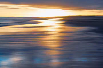 Abstract seascape with blurred golden and blue hues at sunset.