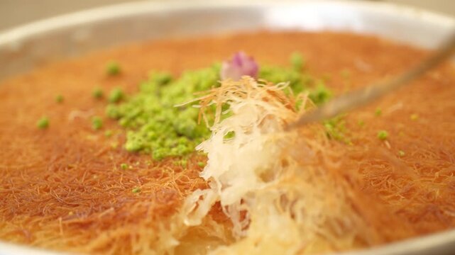 Traditional Middle Eastern knafeh dessert with pistachios and dried rose on a round plate
