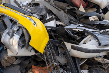 Old and damaged car bumpers collected for recycling. Discarded vehicle bumpers stacked in a...