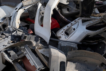 Old and damaged car bumpers collected for recycling. Discarded vehicle bumpers stacked in a...