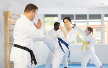 Fototapeta premium Woman and man in white kimono and belts sparring during karate training