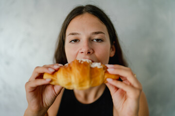 Delightful Morning Indulgence A Young Woman Savoring a Delicious Golden Croissant with a Subtle Smile Enjoying a Sweet Treat Outdoors