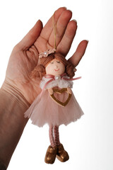 Christmas doll ornament in pink dress holding a golden heart, handmade festive decoration.