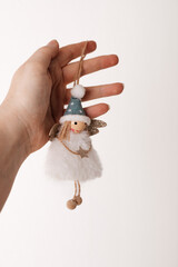 Cute Christmas angel ornament in white dress and blue hat held in hand, isolated on white.