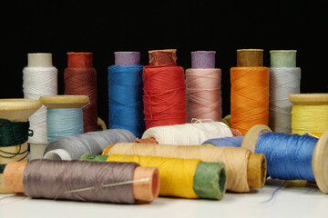 Spools with multi-colored threads on black background, close-up shot