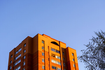 Brick building under clear blue sky during golden hour in a quiet neighborhood