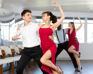 Fototapeta premium Couple of young guy and adult woman dancing tango in studio..