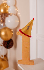 Golden number one with party hat and festive balloon background, first birthday decoration.