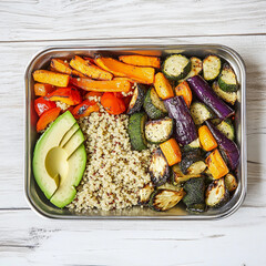 Healthy quinoa bowl with roasted vegetables and avocado on a white wooden background