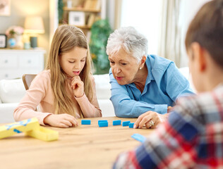Portrait of grandparents and grandchildren having fun together playing domino game at home