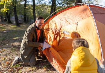 Father happily sets up a tent with son