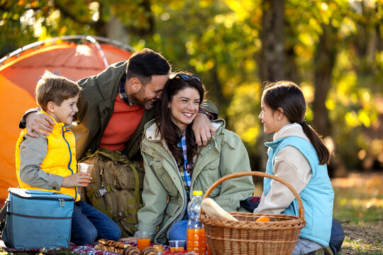 Family sitting down on ground to eat on camping trip