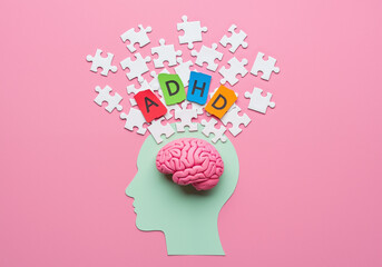 ADHD concept with brain and scattered puzzle pieces on pink background.