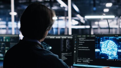 Data center engineer using computer to monitor neural network AI LLM visualization. IT professional using PC to oversee servers powering machine learning processes, camera A