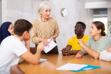 Round table meeting - senior female manager conducts training for employees of different nationalities