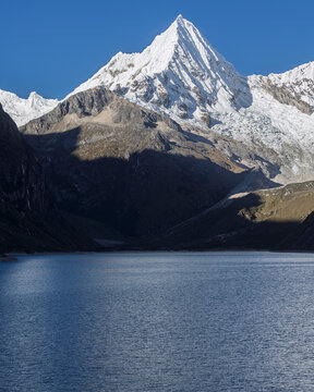 Stunning close-up of Pir&aacute;mide de Garcilaso, a snow-capped peak in the Cordillera Blanca, rising majestically above the deep blue waters of Laguna Paron in Ancash, Peru.