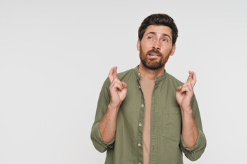 Confident handsome man in shirt cross fingers praying for luck. Portrait of funny male model...