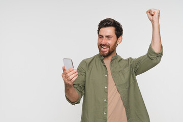 Head shot overjoyed happy millennial Caucasian man holding smartphone, looking at screen, reading...