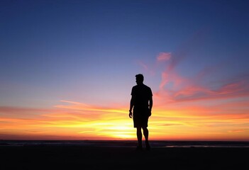 Fototapeta premium Sunset silhouette of solitary figure on ocean beach, waves, relaxation