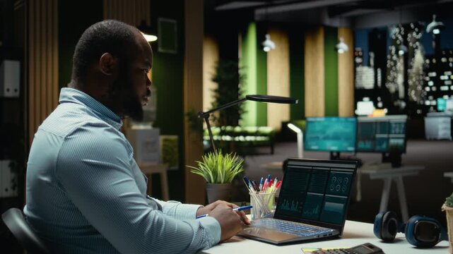 Black consultant reviewing data insights and managing agenda on laptop, drafting reports and proofreading to solve tasks. Notetaking supports goal setting for the business company. Camera A.
