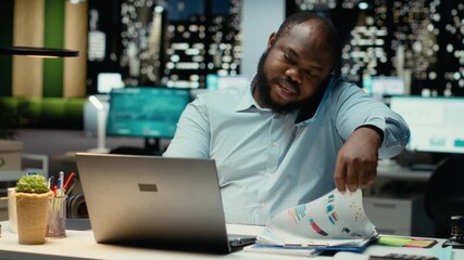 Male employee calling partner on phone for a remote chat late at night, smiling and sharing insight during collaborative chat on telephone line. Adaptability and attentiveness. Camera B.