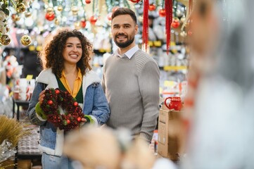 Couple smiling, holding christmas wreath while shopping