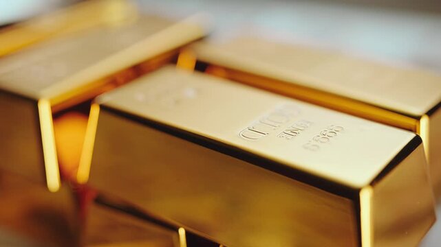 Close-up shot of pure gold bars and ingots stacked together, representing wealth, banking reserves, and investment in precious metals, with shallow depth of field creating soft focus