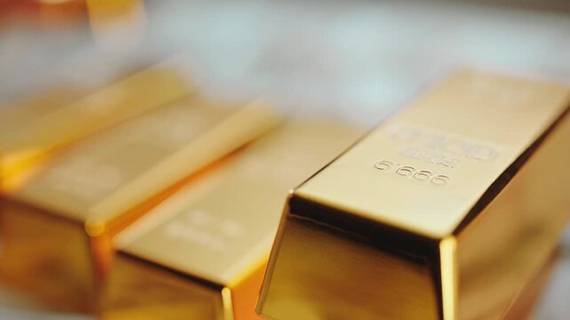 Male hand carefully stacking shiny fine gold bars on a bed of dollar bills, representing wealth, banking reserves, financial security, and a sound investment for the future