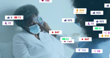 Caregiver measuring masked patient forehead with infrared thermometer at home with media icons