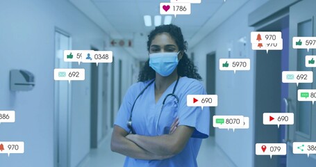 Standing mask wearing nurse crossing arms in hospital corridor, with floating notification icons