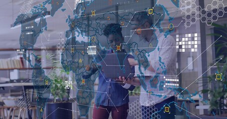 Standing colleagues wearing checked denim shirts holding laptop viewing map data overlay in office
