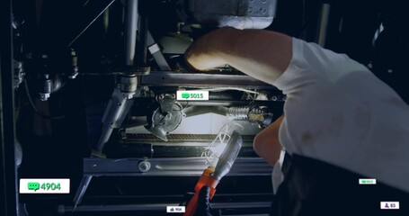 Leaning technician shining work light on motor in maintenance bay, with digital icons, copy space