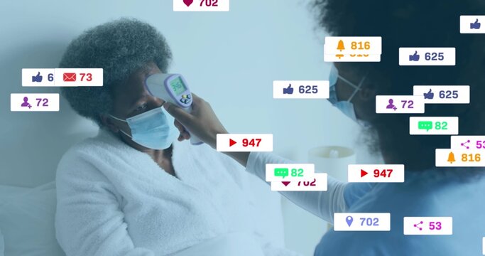 Caregiver measuring masked patient forehead with infrared thermometer at home with media icons
