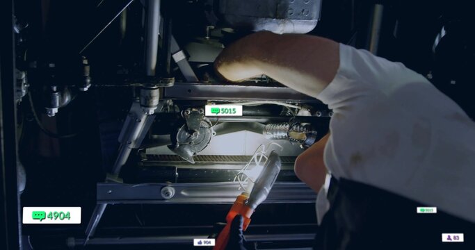 Leaning technician shining work light on motor in maintenance bay, with digital icons, copy space
