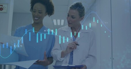 Reviewing doctor and nurse examining reports on clipboard with pen in hospital corridor with charts