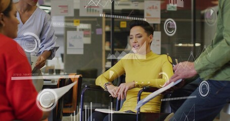 Analyzing group of professionals meeting around table in office, with documents and data overlays