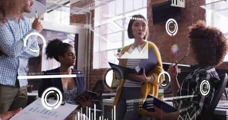 Collaborating four staff analyzing data overlays in open-plan office, holding tablets, notebooks