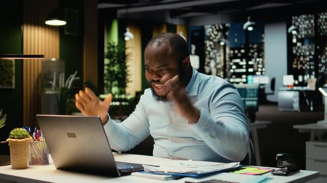 Overjoyed delighted guy reading good news in his emails at night, celebrating a career breakthrough and beaming in the office. Businessman with awesome opportunity and contract offer. Camera A.