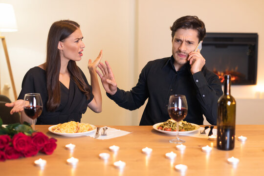 A couple sits at a dining table with pasta dishes and wine, but tension arises as one partner argues while the other talks on the phone. Candles and roses add to the atmosphere. - Powered by Adobe