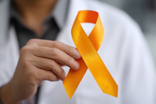 Doctor hand holding an orange awareness ribbon, symbolizing support and solidarity for a specific cause or disease - Powered by Adobe