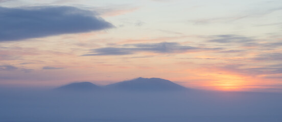 Winter arctic landscape. Beautiful sunset views of the snow-covered tundra and mountains. Cold weather. Frosty fog over the tundra. Winter panorama. Chukotka, Siberia, Far North of Russia, Arctic.