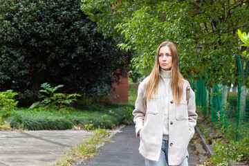 Young woman walking along a tree-lined path in an urban park