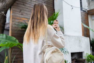 Young woman with long hair looking at her reflection in a small mirror outdoors