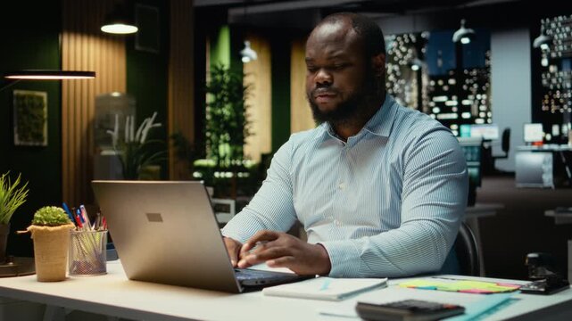 African american analyst pondering about possible outcomes for a problem at workstation after hours, intense concentration to evaluate projections with logical deduction and observation. Camera A.