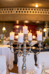 Elegant candelabra with lit candles at a beautifully set dining table in a warm restaurant during an evening event